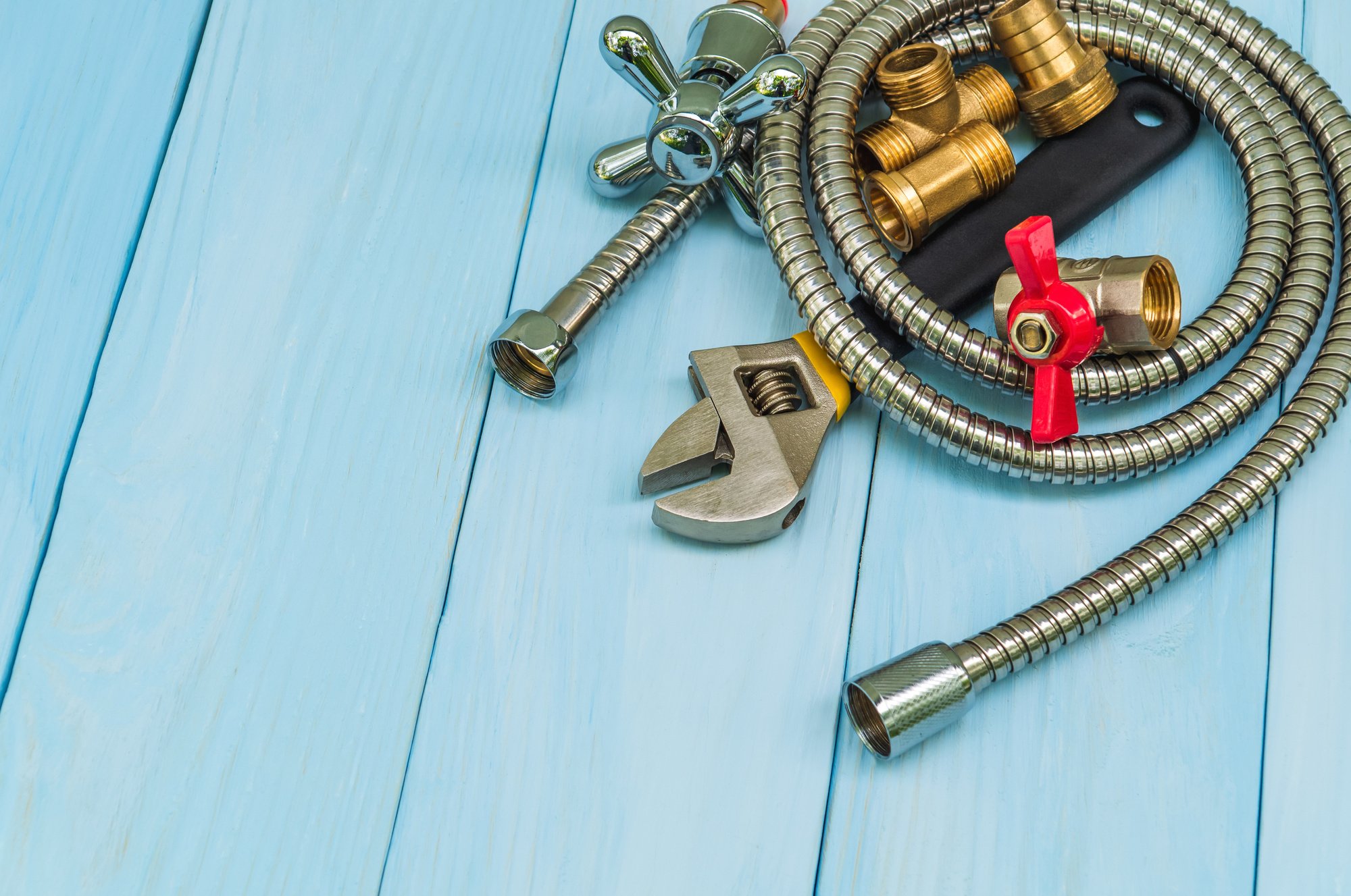 Plumbing tools and a hose on blue boards were prepared by a craftsman before repair